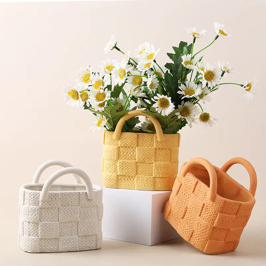 Three woven ceramic baskets with handles, two of which contain flowers, on a light background.