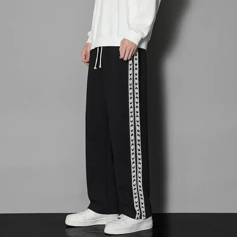 Person wearing black pants with white chain design on a gray background
