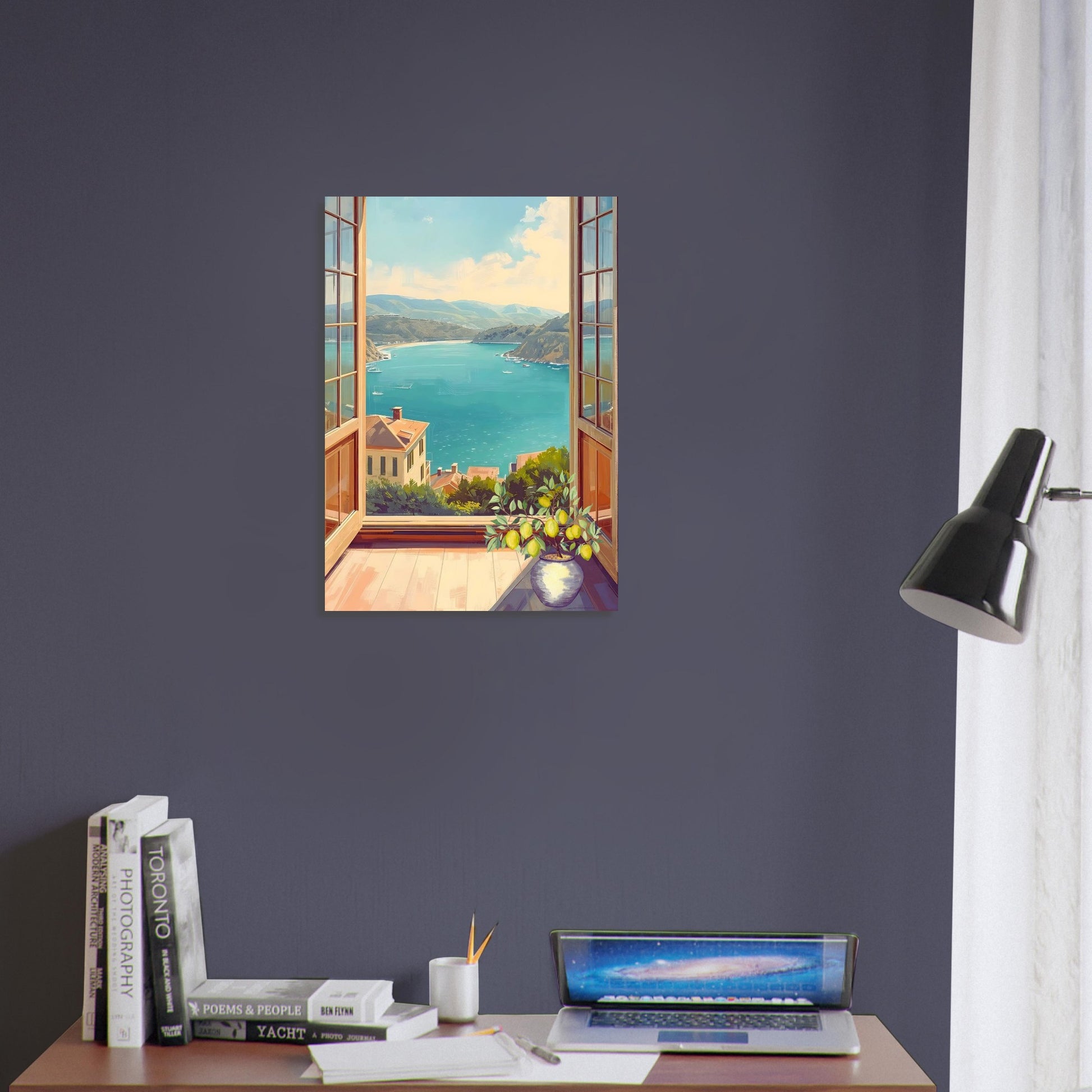Art print of a scenic view of a lake on a wall above a desk with books and a laptop.