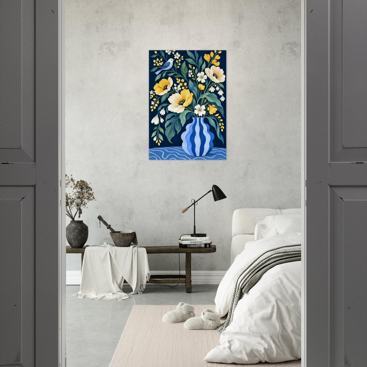 A vertical canvas print of a floral still life painting in blue, yellow, and white, displayed on a textured light gray wall in a modern bedroom setting.