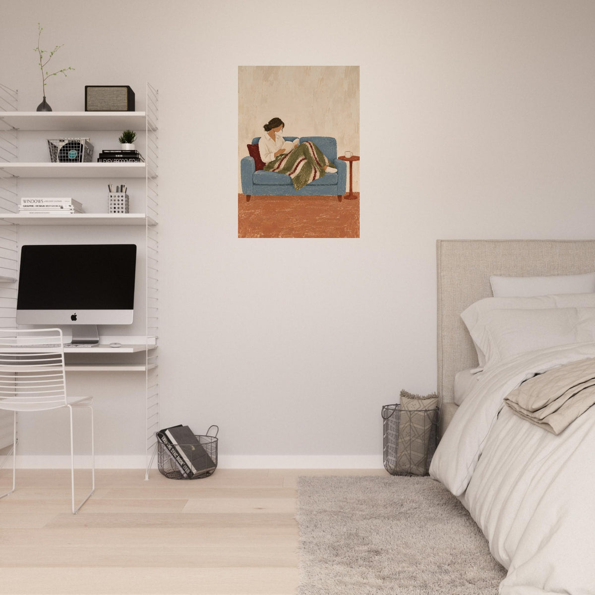 A vertical art print depicting a woman reading on a blue sofa, styled on a bedroom wall above a bed and next to a white desk setup.