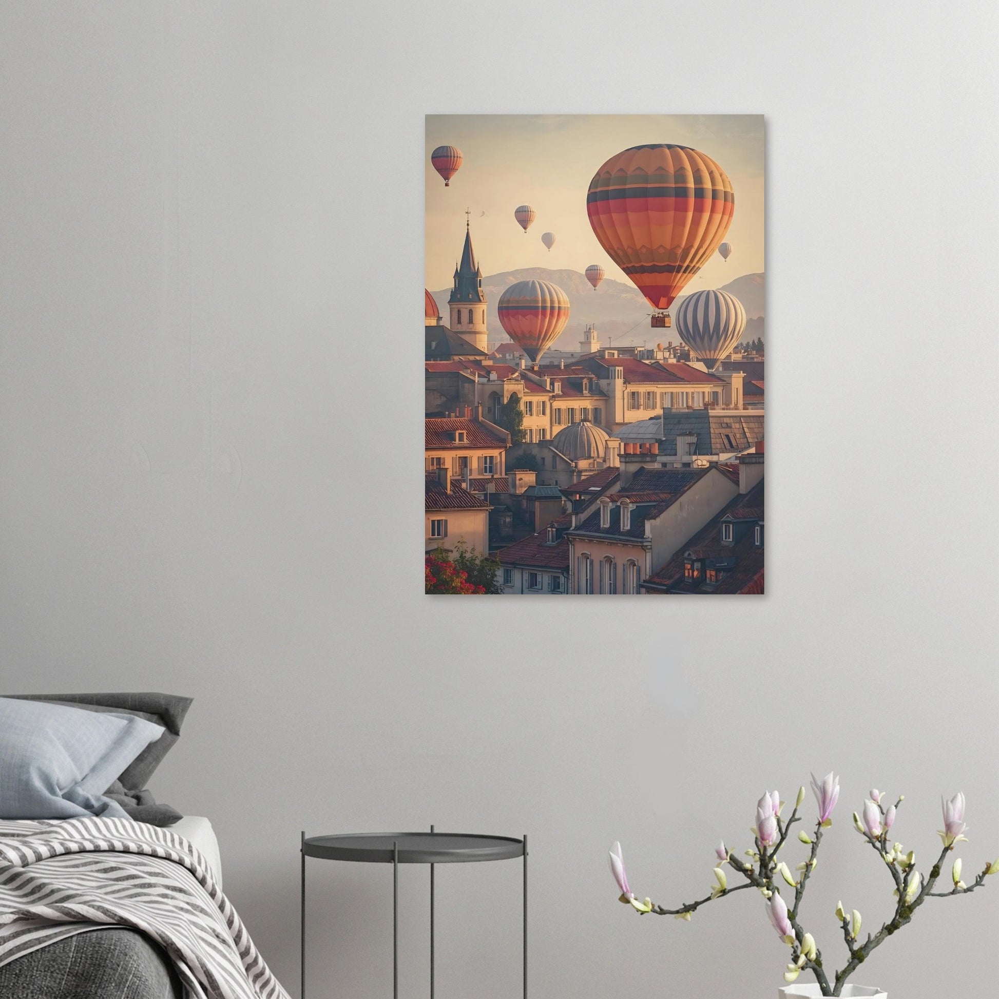 Canvas print of hot air balloons over a town on a gray wall above a bed.