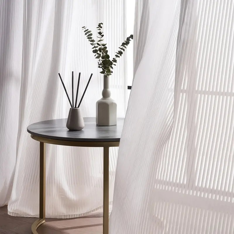 Small round table with decorative items against a white curtain backdrop