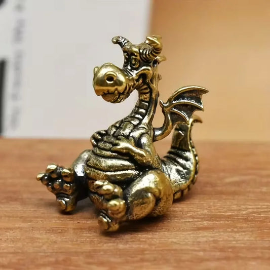 Mini brass dragon figurine vintage style small decorative dragon ornament sitting on wooden surface