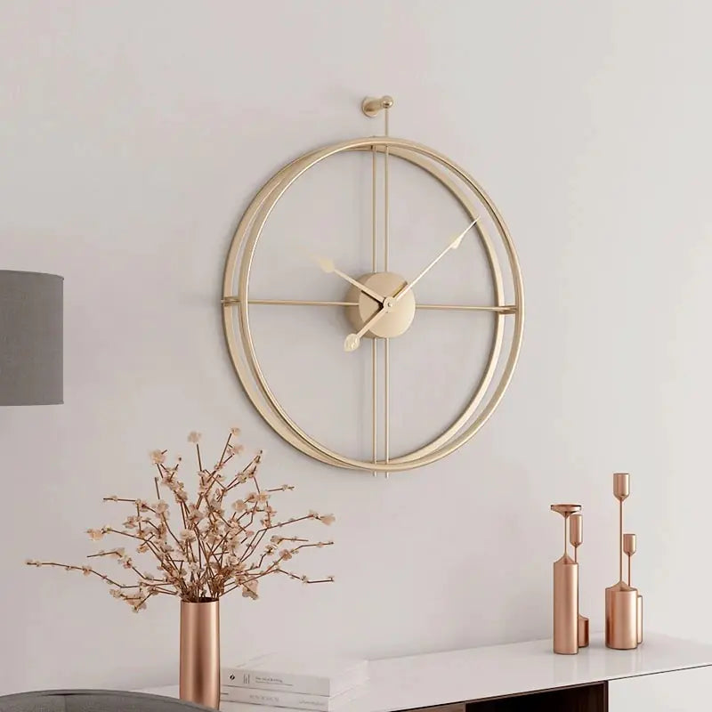 Gold wall clock on a white wall with decorative elements below.