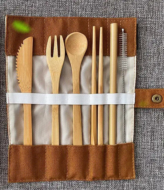 Bamboo cutlery set including knife, fork, spoon, straw, and brush in a reusable fabric pouch on grey background