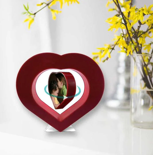 Heart-shaped photo frame with a couple's picture inside, placed on a white surface with yellow flowers in the background.