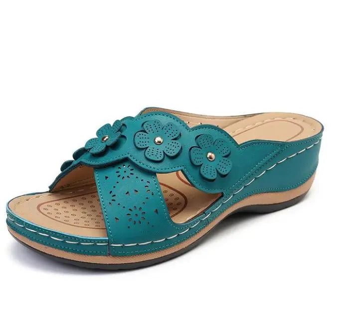 Teal sandal with floral designs on a white background