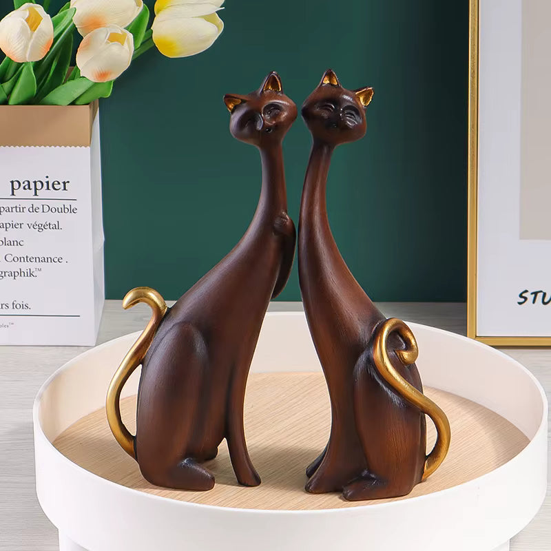 Pair of decorative resin cat sculptures with elongated modern silhouettes and artistic finishes, displayed as contemporary home decor on a tabletop.