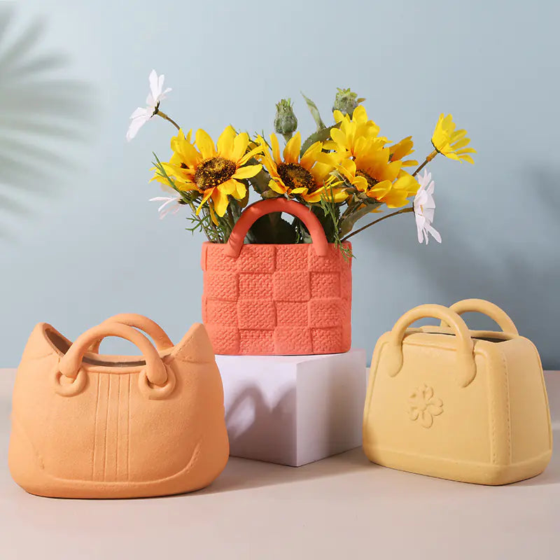 Three colorful ceramic handbags with floral arrangements on a light blue background