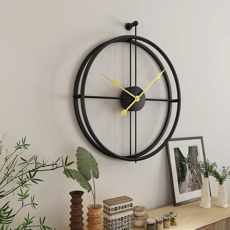Decorative wall clock with black metal frame and yellow hands on a light gray wall.
