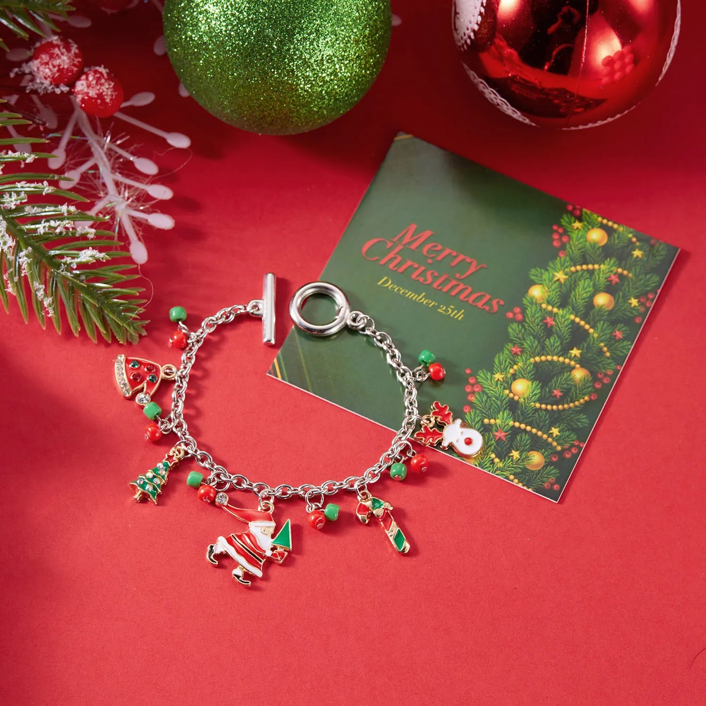 Christmas-themed bracelet with charms on a red surface with a 'Merry Christmas' card.