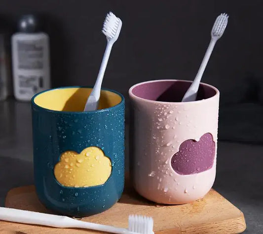 Two eco-friendly toothbrush cups with cloud design, shown with toothbrushes on a wooden tray in a modern bathroom setting