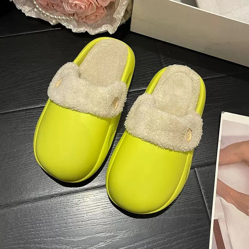 Pair of bright green slippers with fluffy white interior on a dark wooden surface.