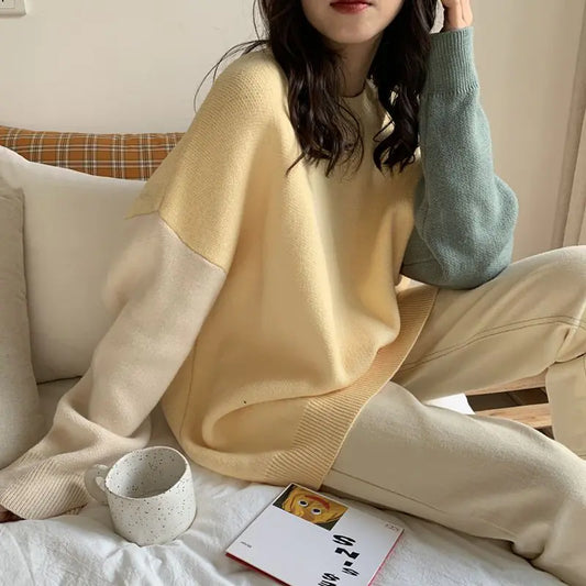 Person wearing a beige and white sweater sitting on a couch with a mug and book.