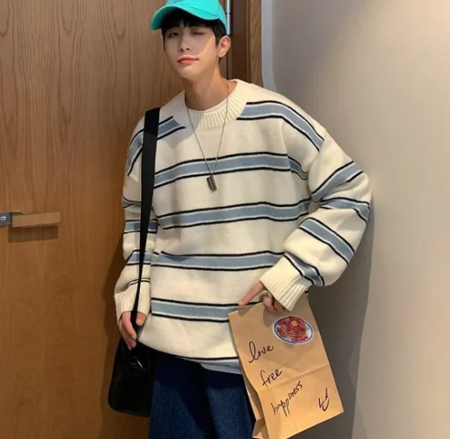 Person wearing a striped sweater and cap, holding a paper bag with text.