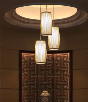 Three pendant lights hanging from a ceiling with a decorative wall in the background.