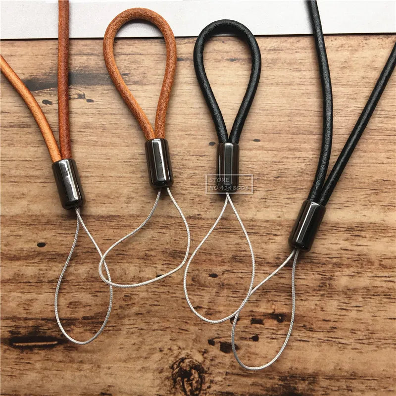Two leather lanyards with metal ends on a wooden surface