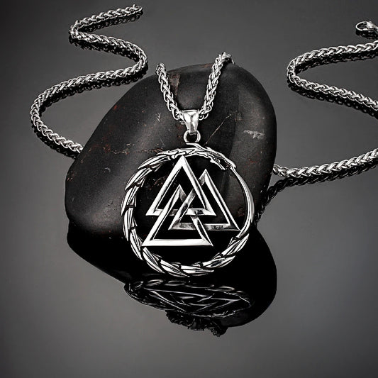 Silver necklace with a triangular pendant on a dark stone surface