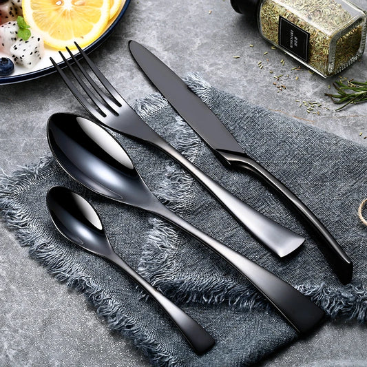 Black stainless steel cutlery set with knife, fork, spoon and dessert spoon on cloth napkin