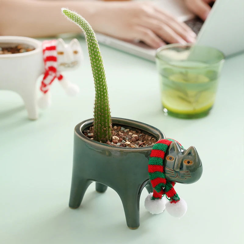 Dark green ceramic cat planters displayed with cacti on a light green table