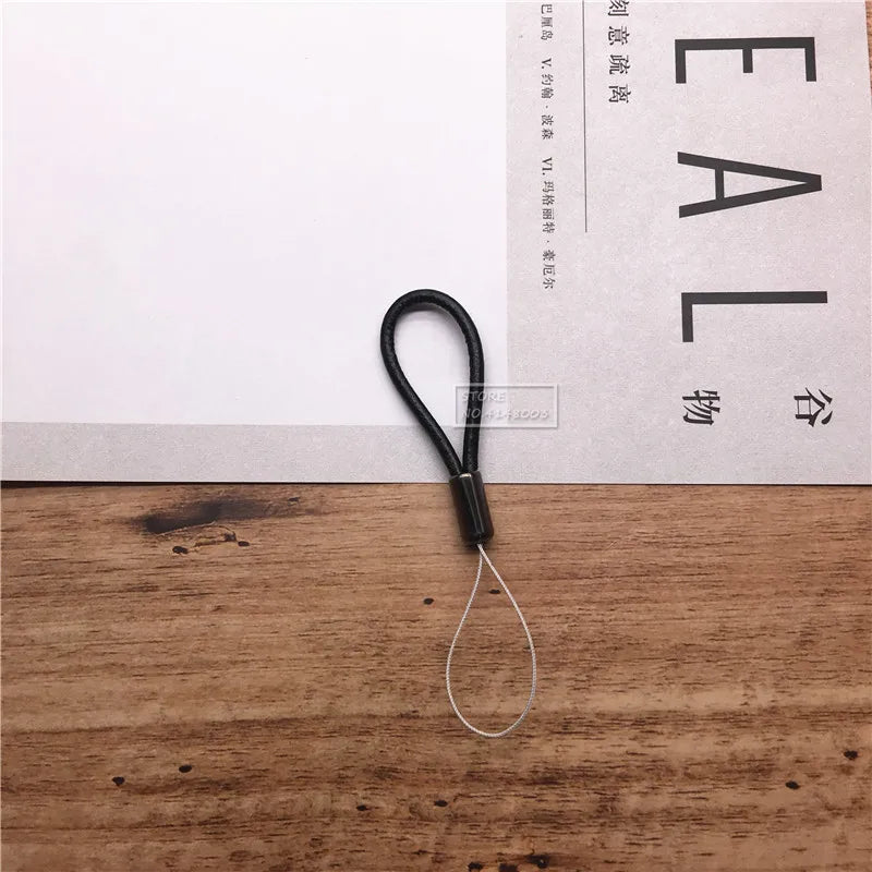 Black lanyard on a wooden surface with a white paper background