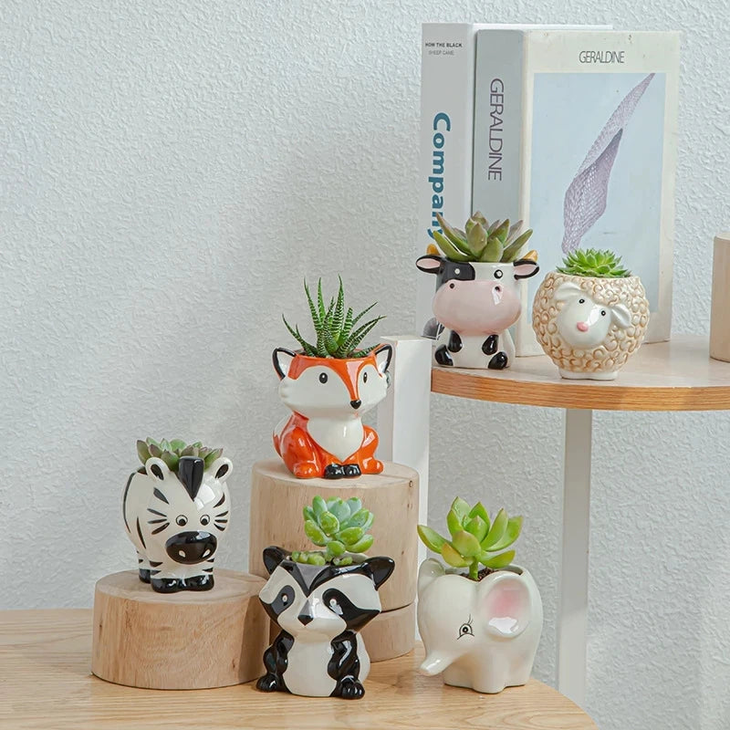 Set of animal-themed ceramic planters on a wooden surface with a light gray wall background.