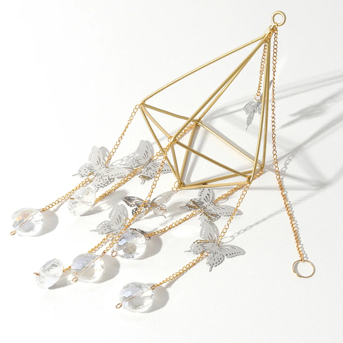 Decorative hanging plant holder with geometric design, crystals, and butterfly elements on a white background.