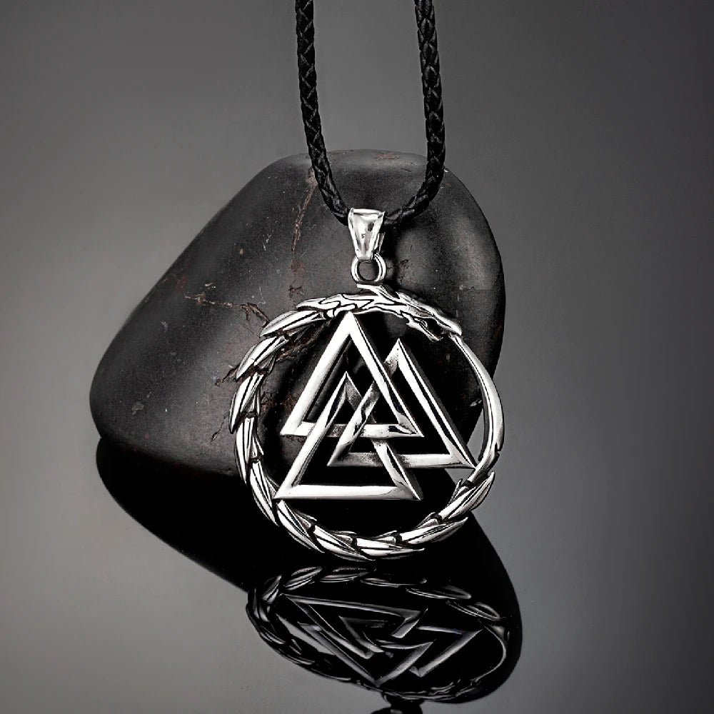 Silver Valknut pendant on a black cord against a dark stone background