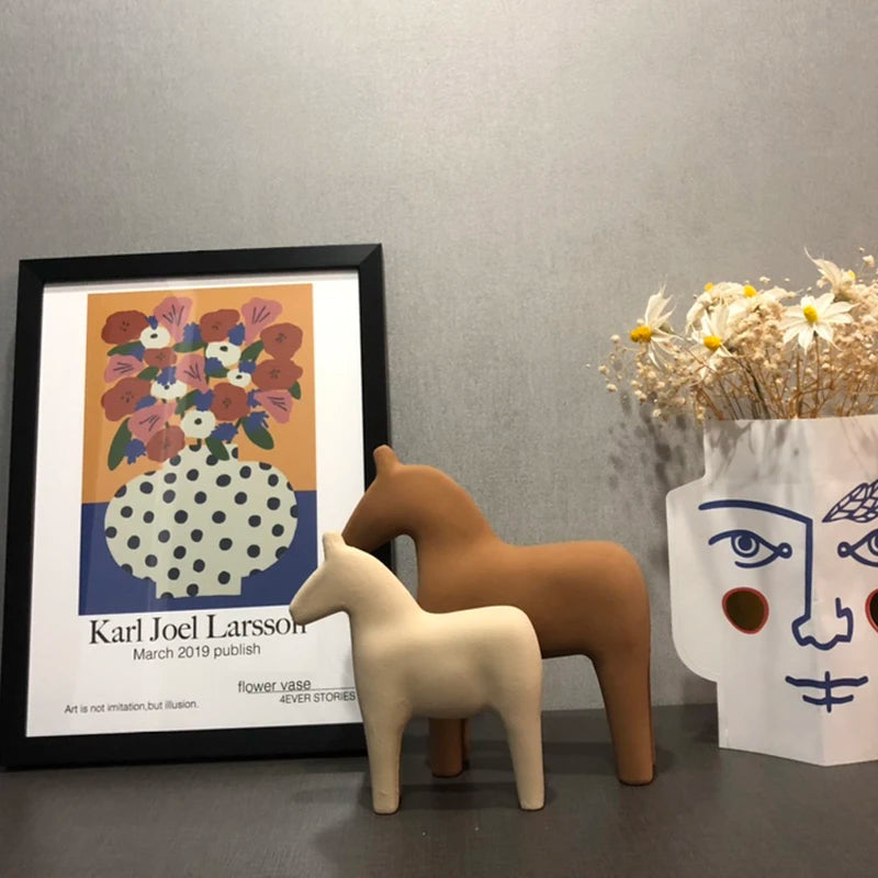 Decorative items including a framed poster, ceramic horses, and a vase with flowers on a gray surface.