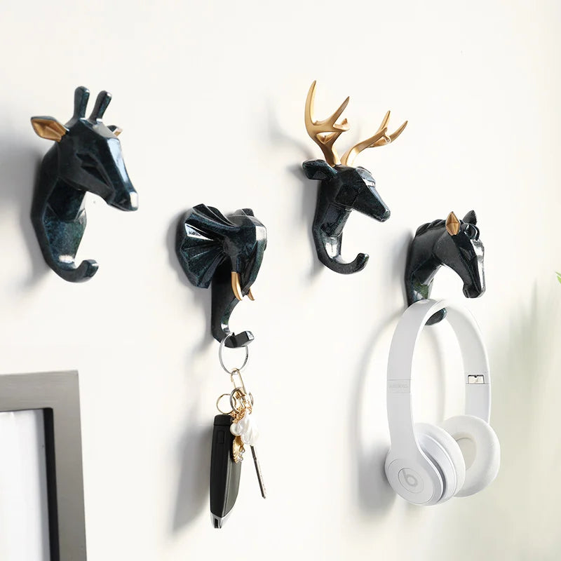 Wall hooks shaped like animal heads with a pair of white headphones hanging on one of them.