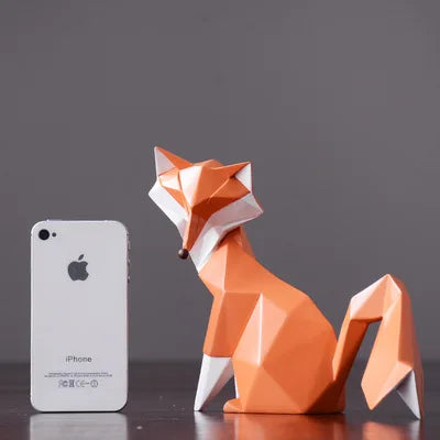 Orange origami fox model next to an iPhone on a dark surface with a gray background