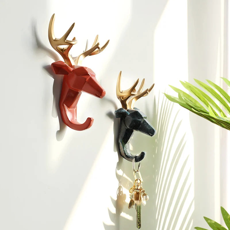 Two wall hooks shaped like deer heads with gold antlers on a light background.