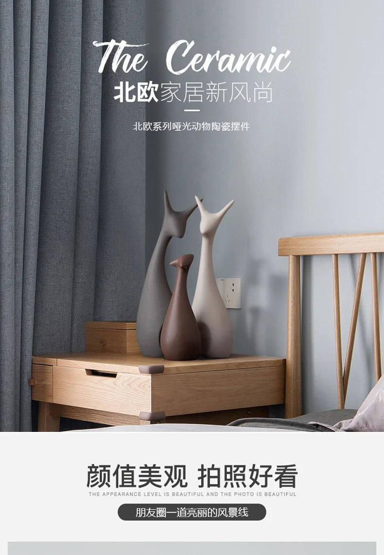 Decorative ceramic deer ornaments on a wooden side table with gray curtains in the background.