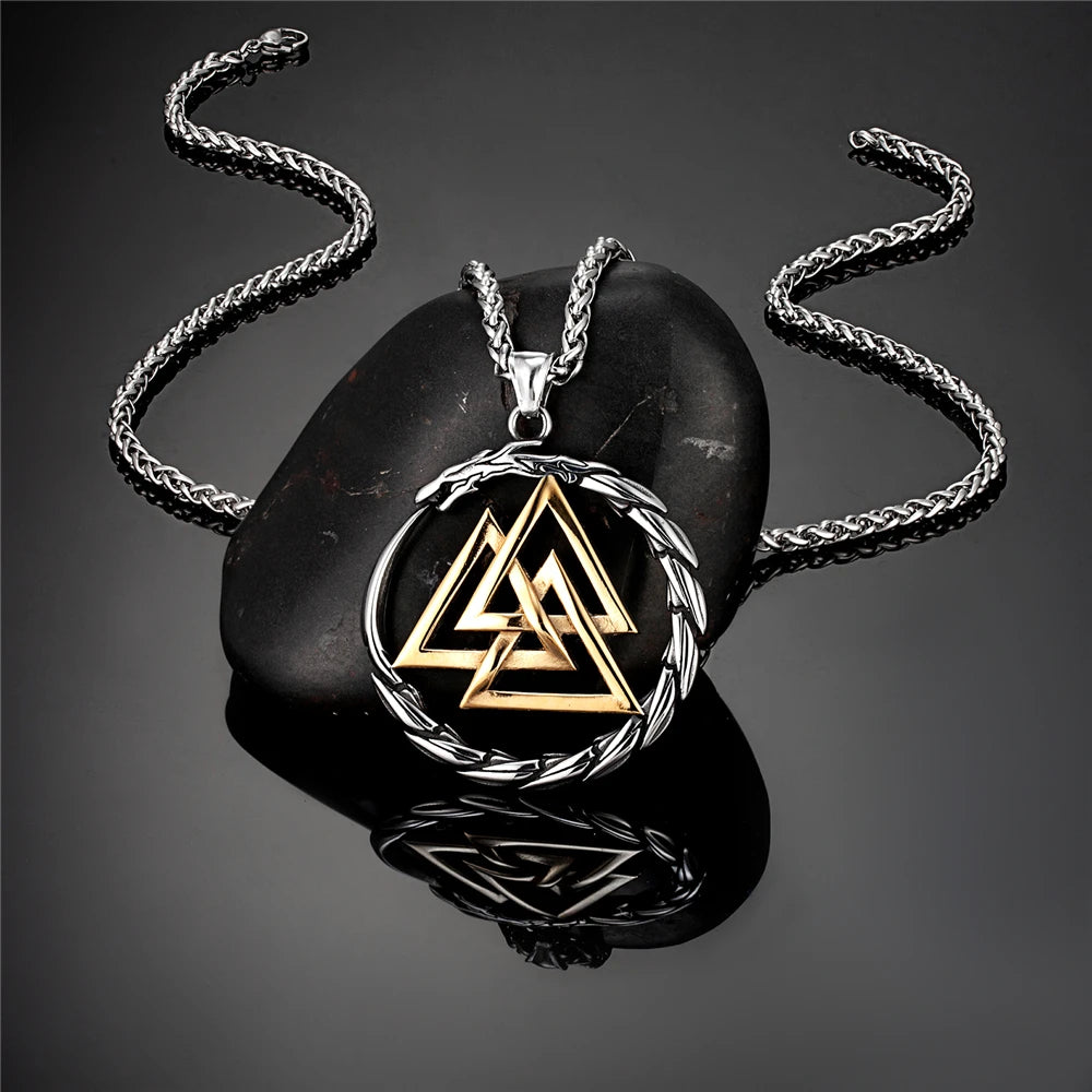 Gold and silver necklace with a triangular design on a dark stone surface