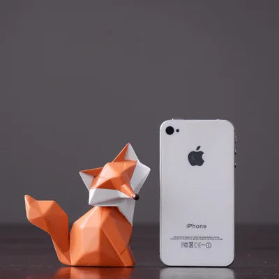 Orange origami fox next to a white iPhone on a dark background