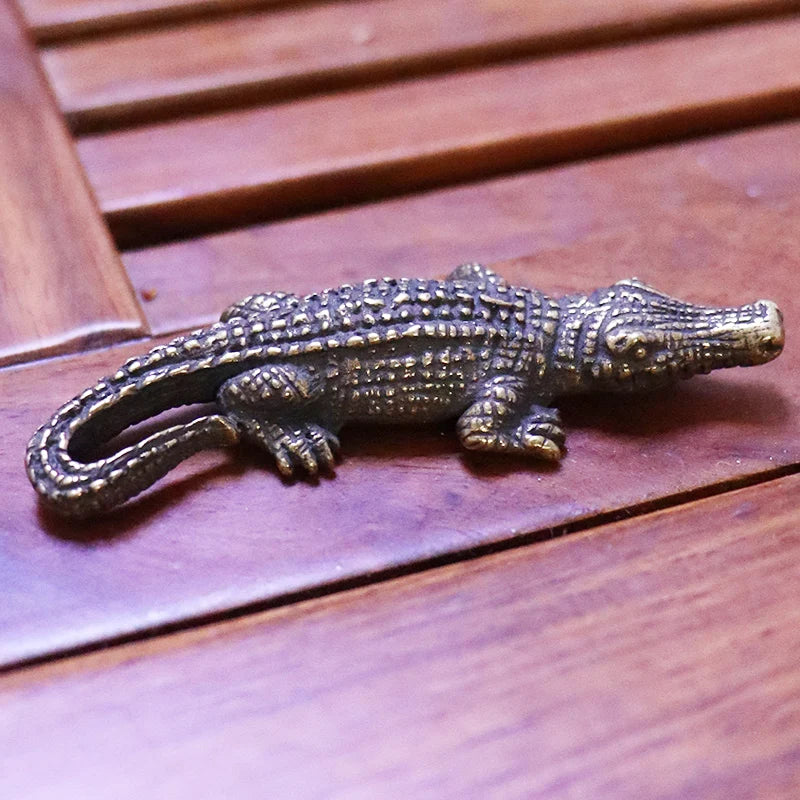Bronze alligator-shaped door handle on a wooden surface
