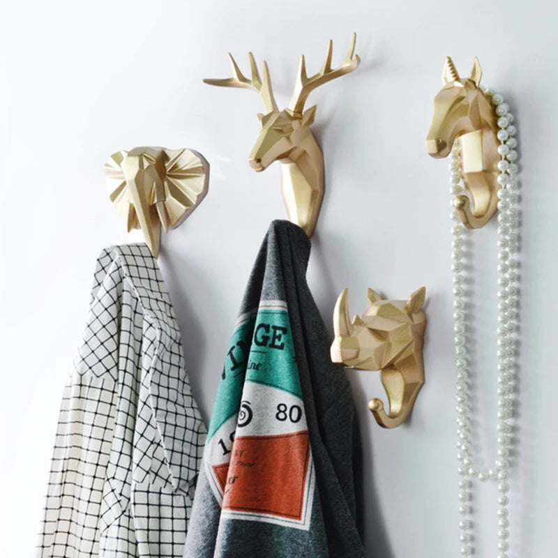 Gold animal head wall hooks with clothes on a white wall