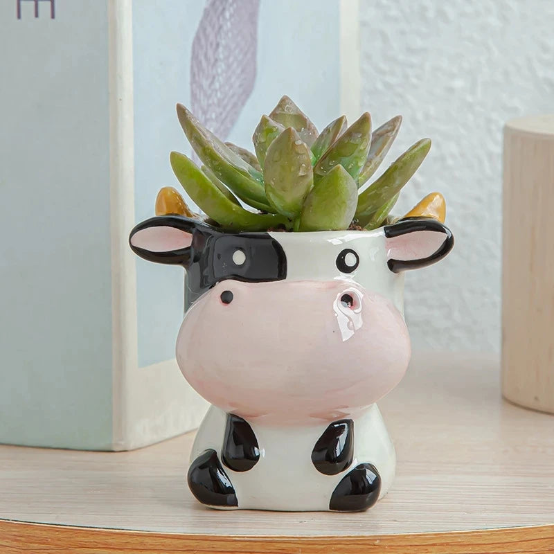 Cow-shaped planter with succulent plant on a wooden surface