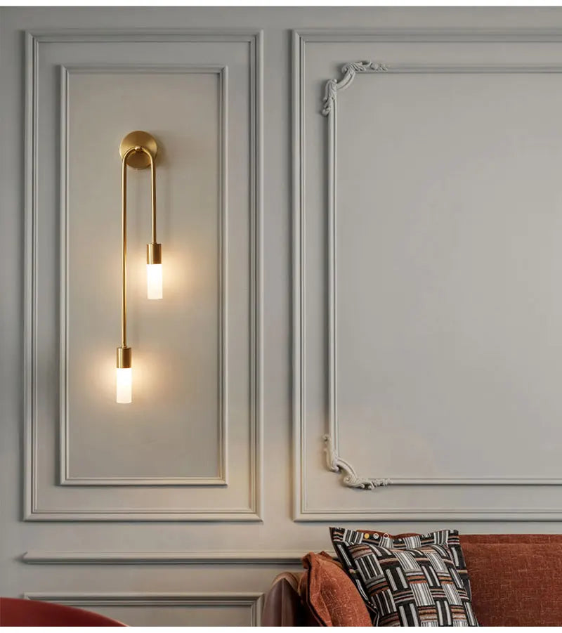 Decorative wall sconce on a wall with molding and a patterned pillow.