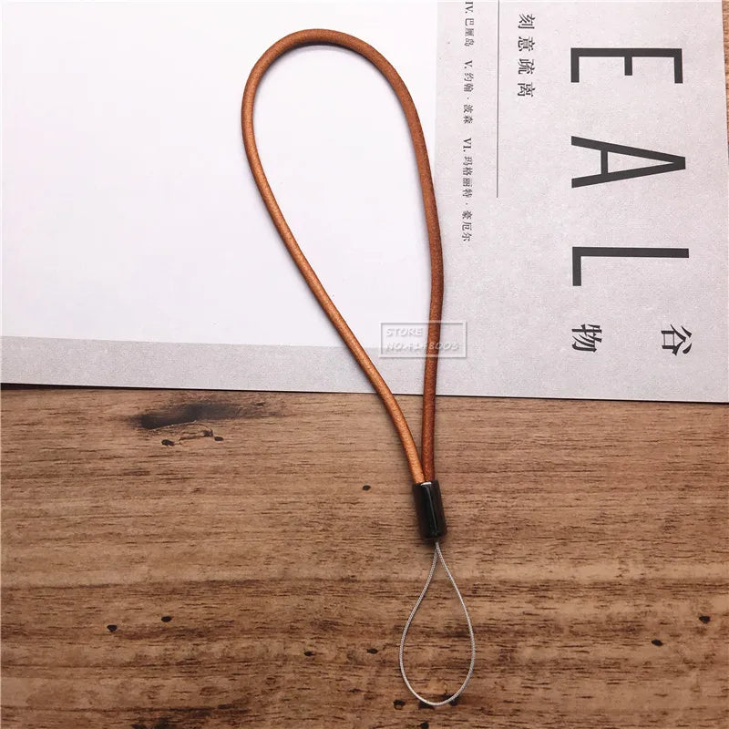 Brown leather lanyard with a metal hook on a wooden surface with Chinese text in the background.