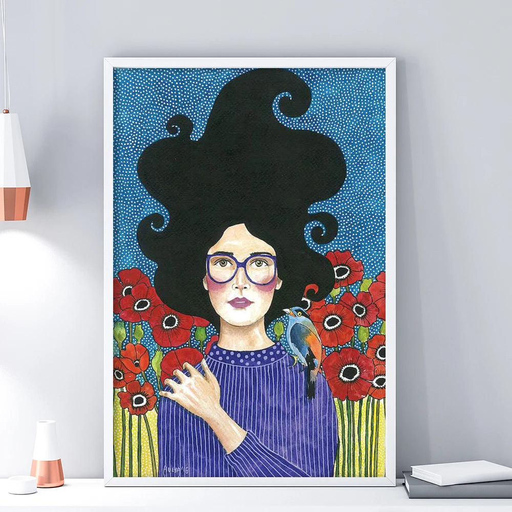 Framed artwork of a woman with black hair, glasses, and flowers on a blue background.