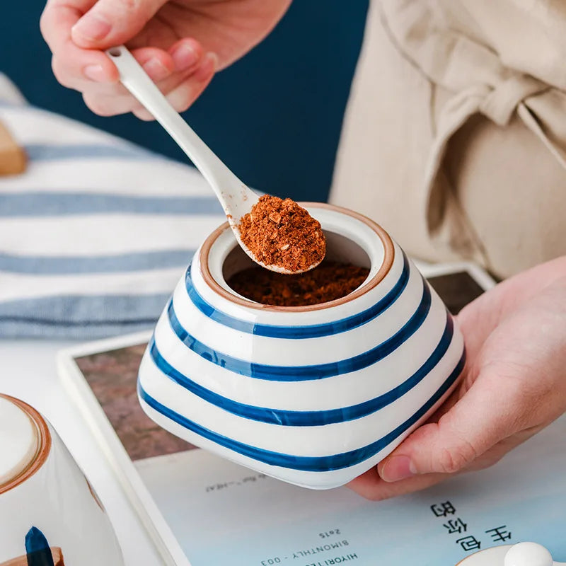 Person scooping spice from a blue and white striped japanese ceramic spice jar