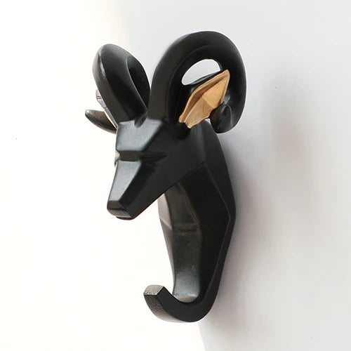 Black and gold wall hook shaped like a ram's head on a white background