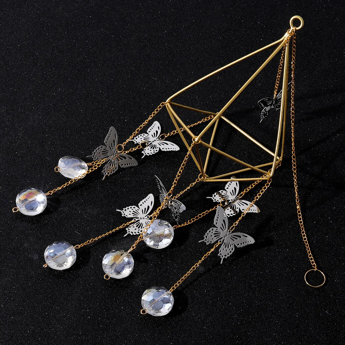 Decorative hair accessory with geometric design, butterfly elements, and crystal-like beads on a black background.