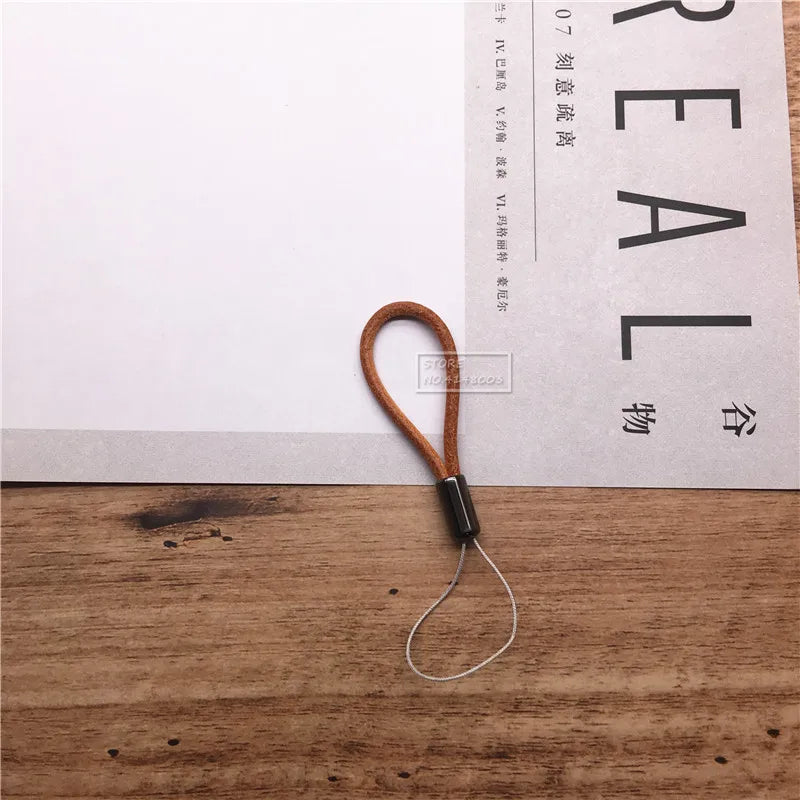 Brown leather lanyard with metal clip on a wooden surface with text in the background