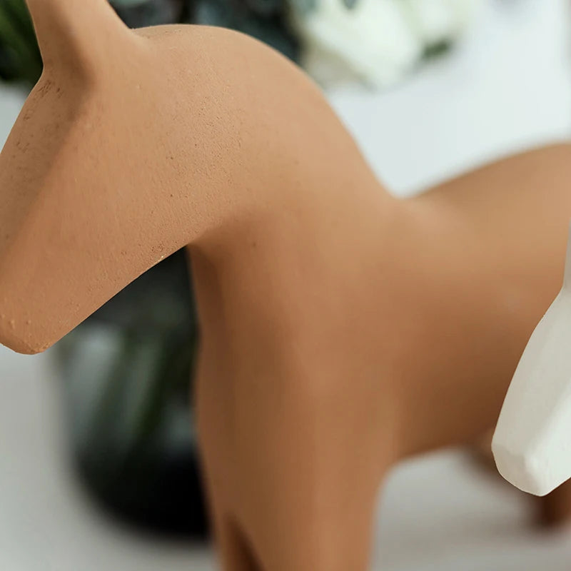 Close-up of a terracotta-colored ceramic deer figurine on a blurred background