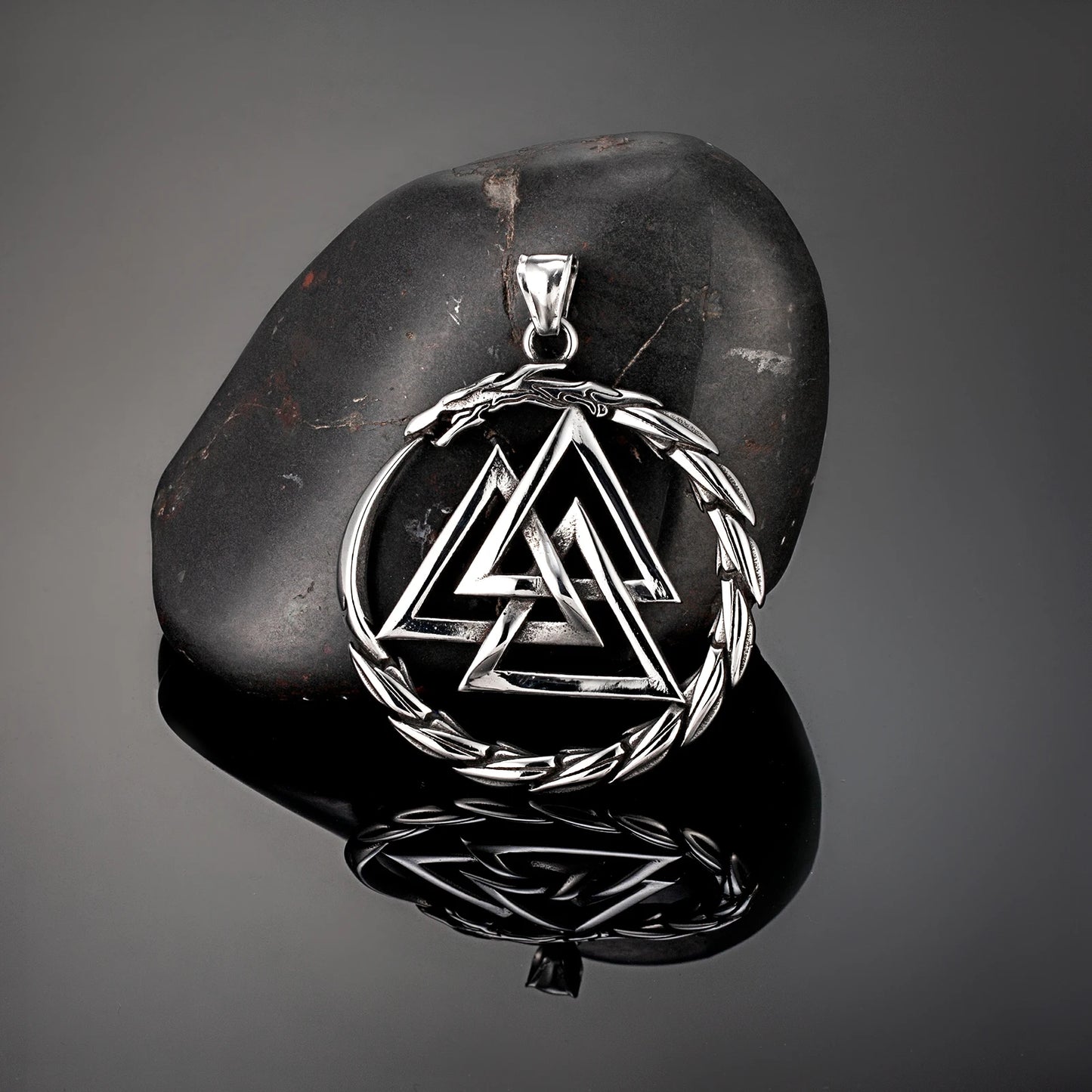 Silver Valknut pendant on a dark stone surface