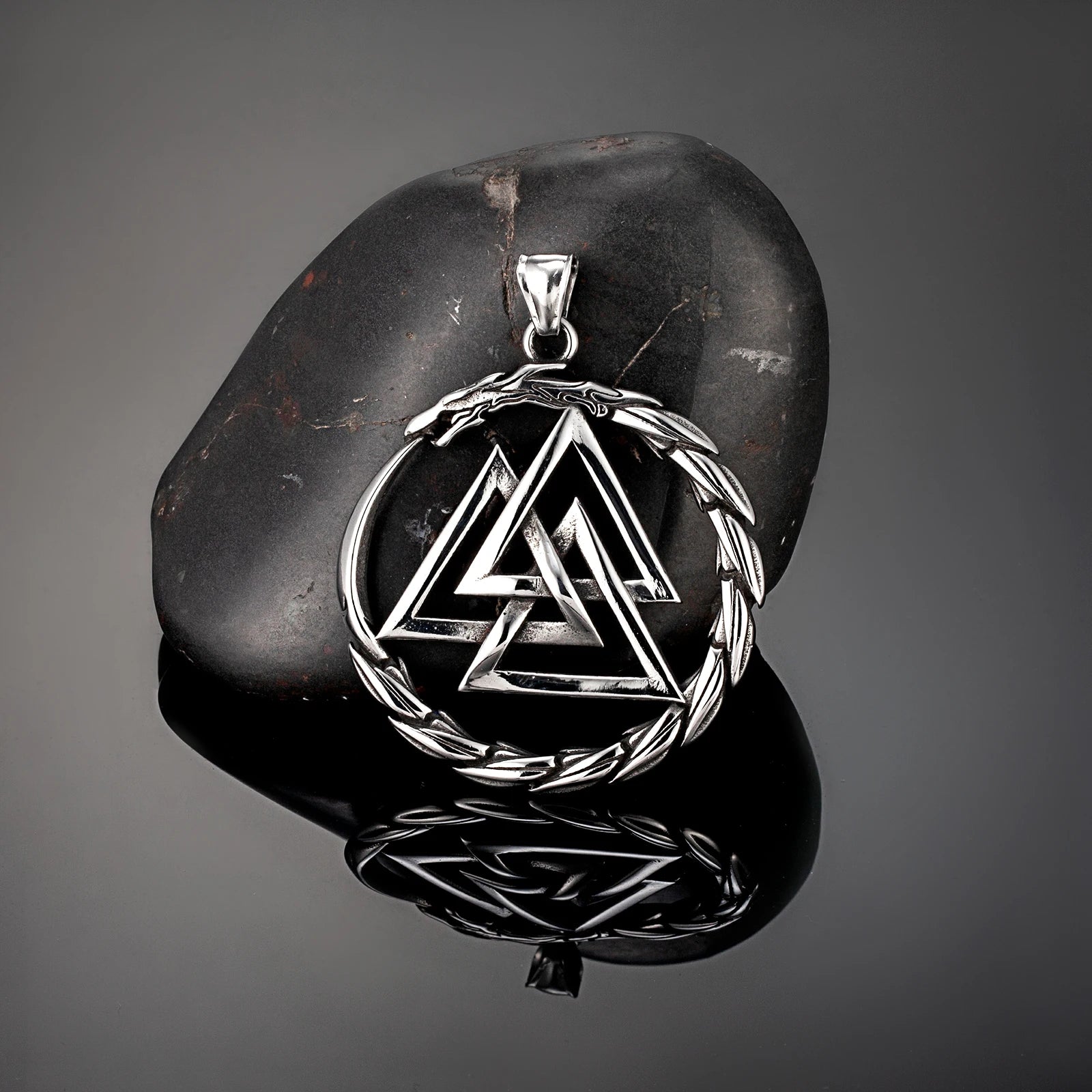 Silver Valknut pendant on a dark stone surface