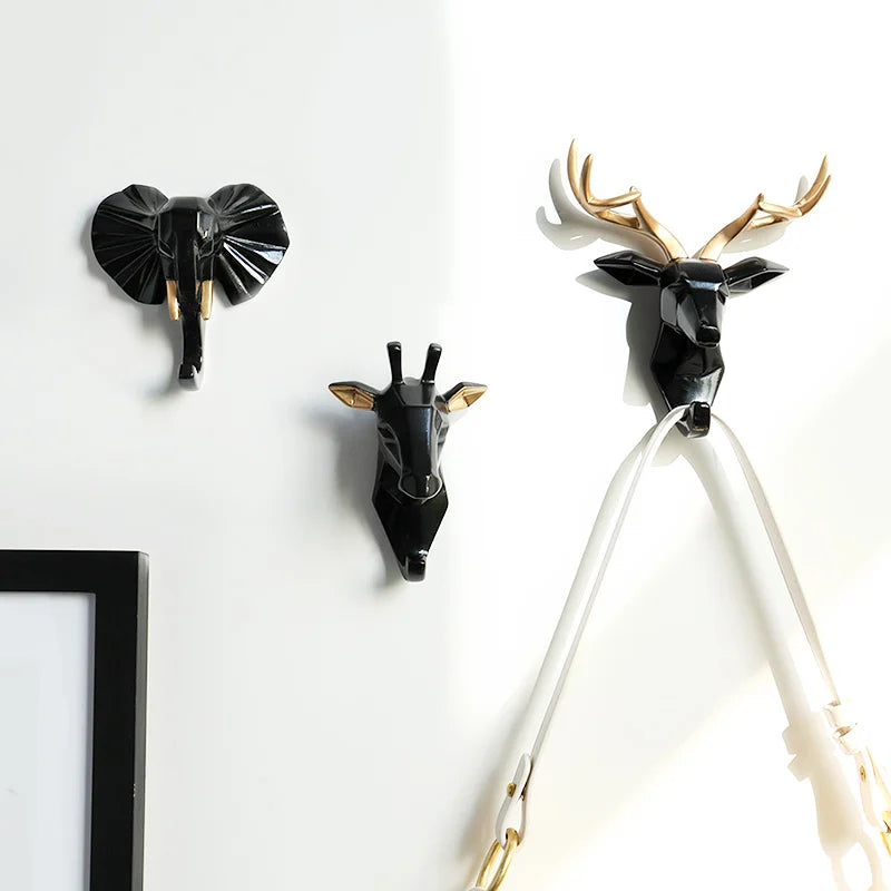 Decorative wall hooks shaped like an elephant, deer, and giraffe on a white background